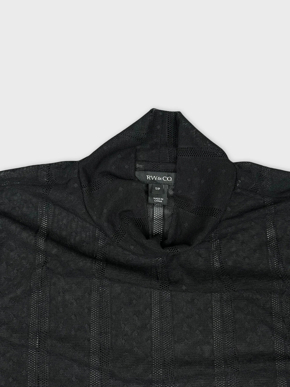Detail view of a black long sleeve top featuring a textured pattern.