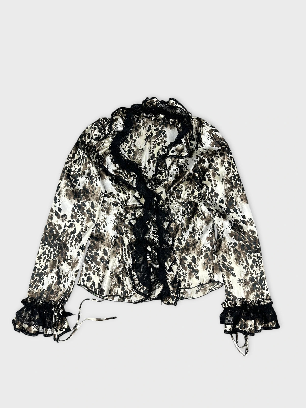 Detail view of a long sleeve top in cream with a black floral pattern.