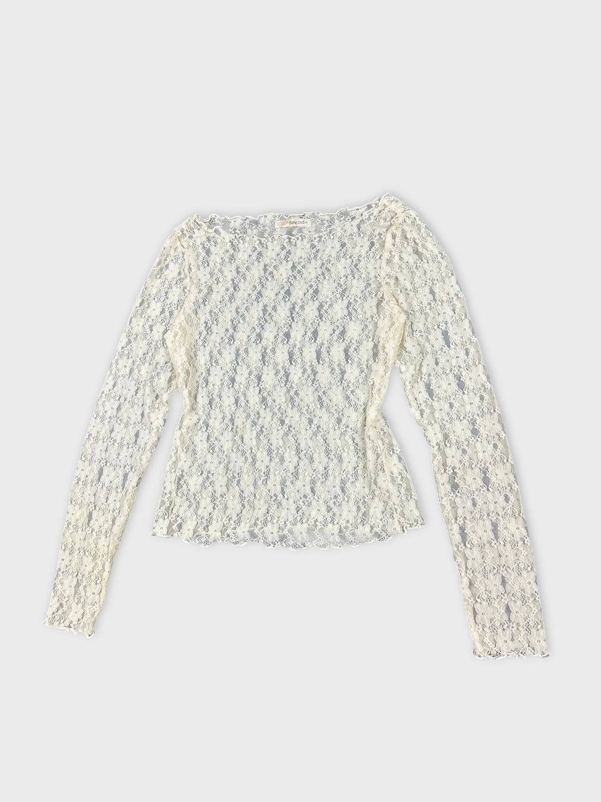 Detail view of long sleeve lace top in off-white color.