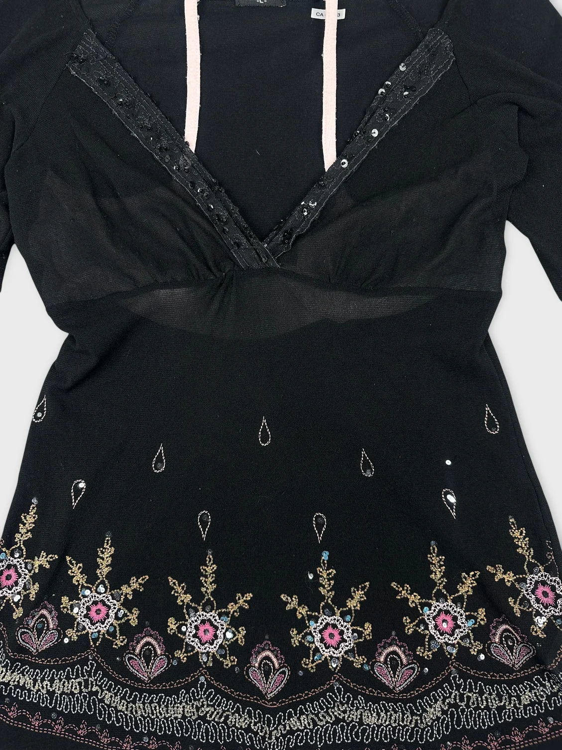 Detail view of a black long sleeve top with embroidered floral pattern.