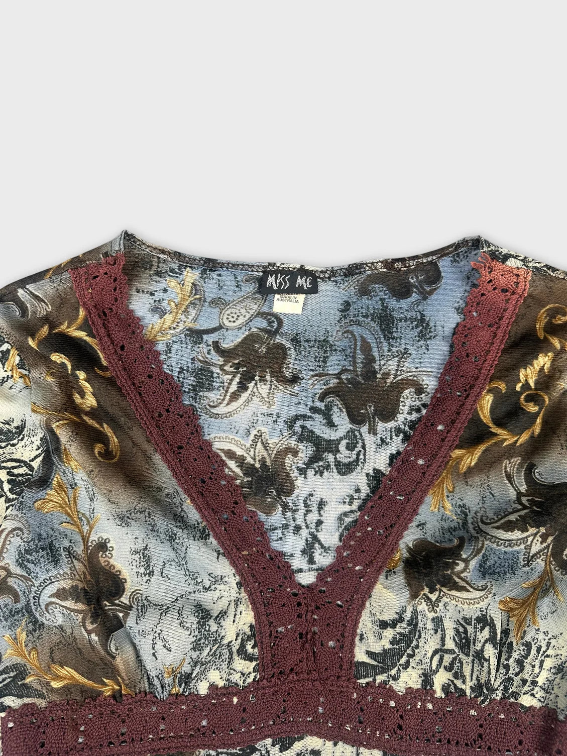 Detail view of a vintage long sleeve top in blue with burgundy lace trim.