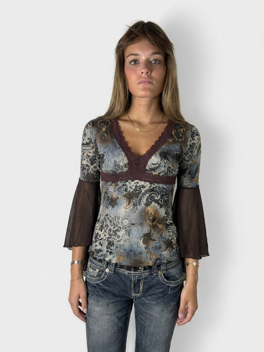 Front view of a long sleeve top in blue with floral patterns and lace trim.