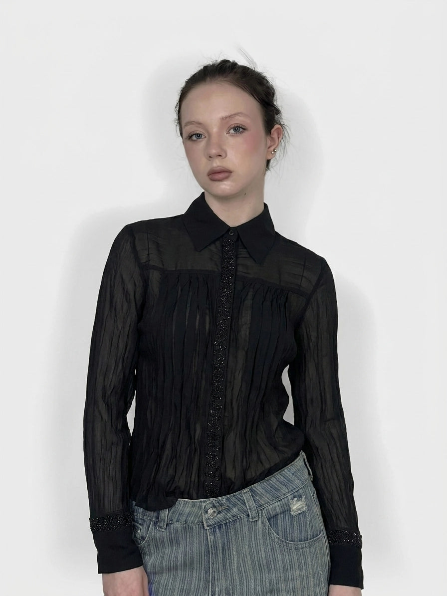 Black long sleeve top with pleats and beaded trim, front view.