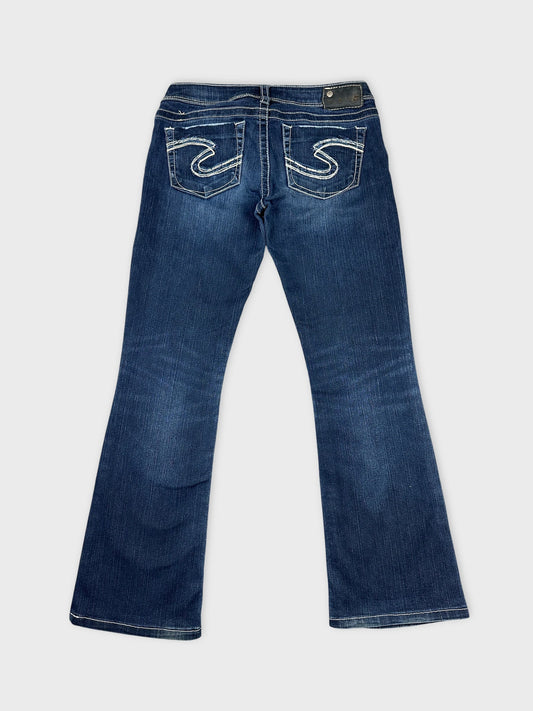 Back view of long wide jeans in dark blue with embroidered pockets.