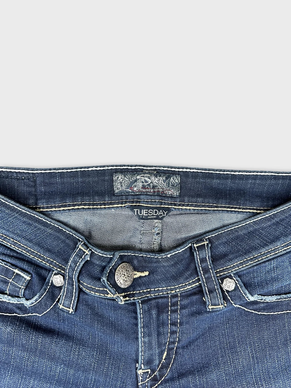 Detail view of women long wide jeans in dark blue with button embellishments.