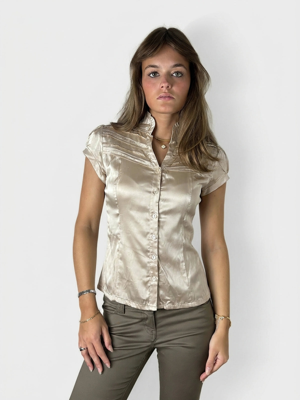 Front view of a short sleeve button-up shirt in beige satin with pleated detail.
