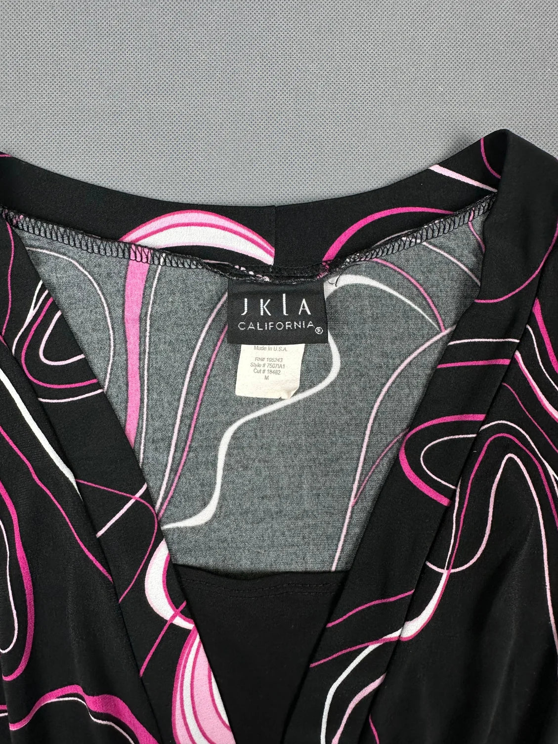 Detail view of a black short sleeve shirt with pink and white swirls.