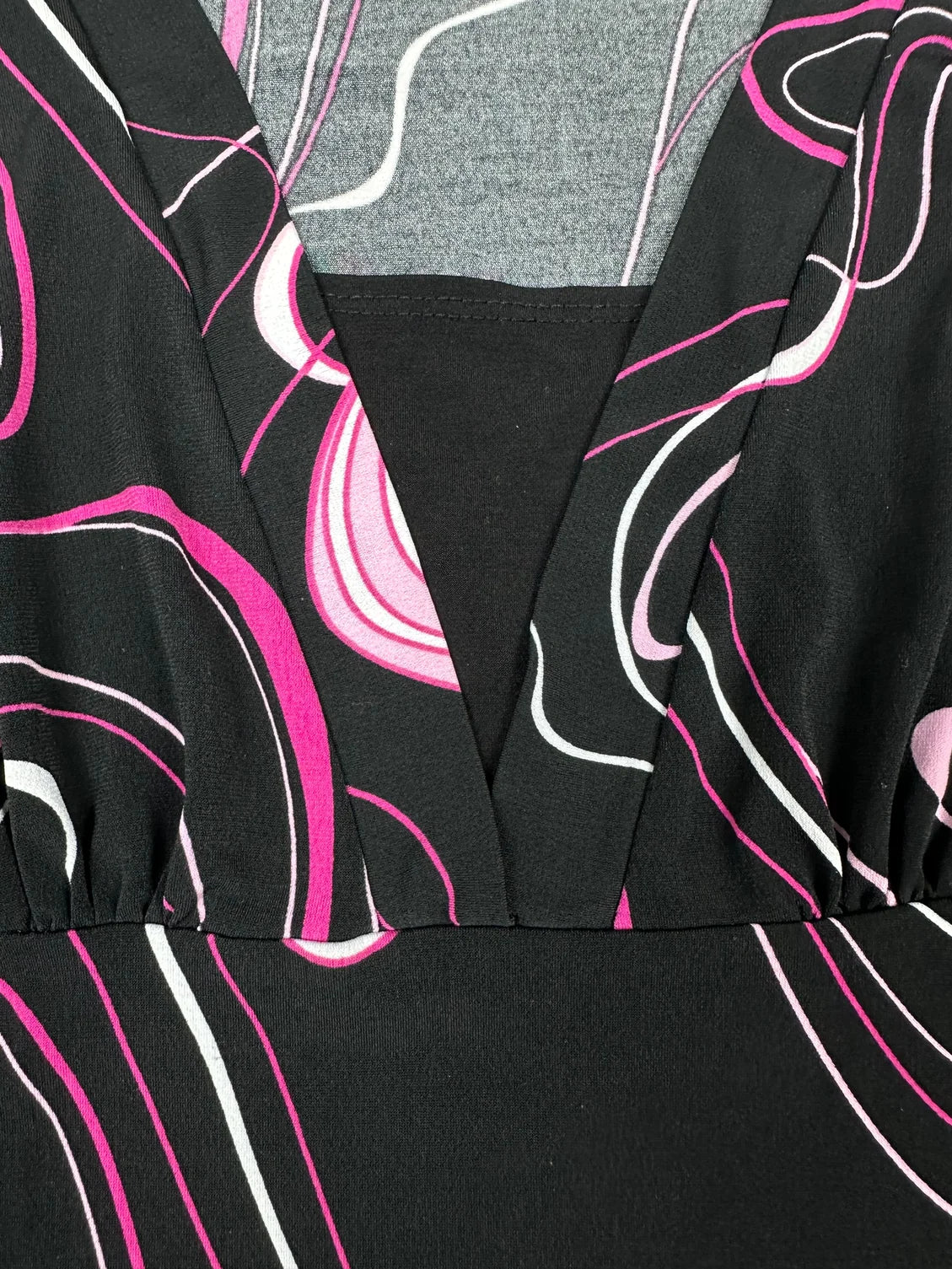 Detail view of a short sleeve black shirt with pink and white abstract patterns.