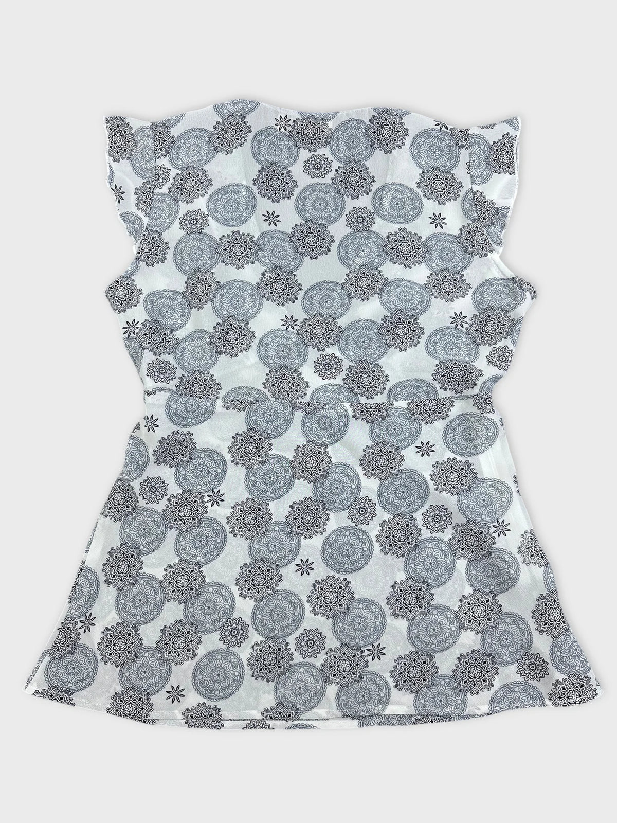 Back view of a short sleeve top in white with black floral pattern.