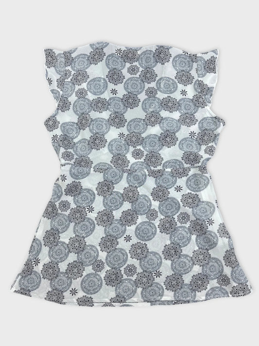 Back view of a short sleeve top in white with black floral pattern.