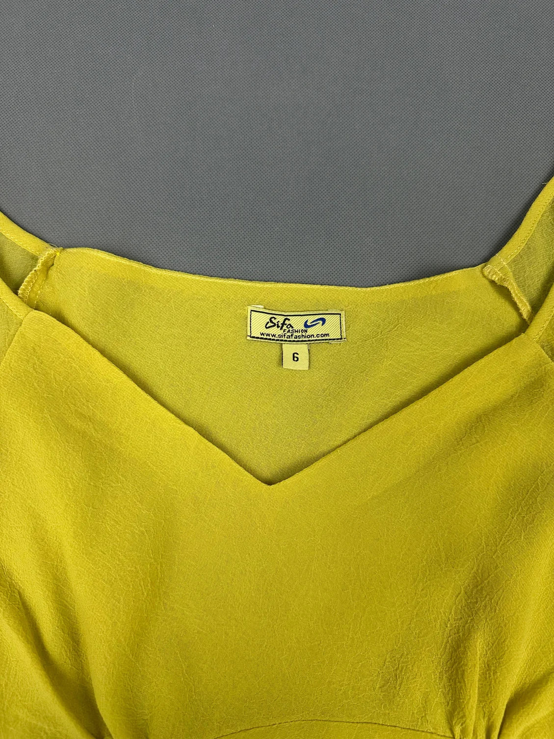 Detail view of yellow short sleeve top with V-neck design.