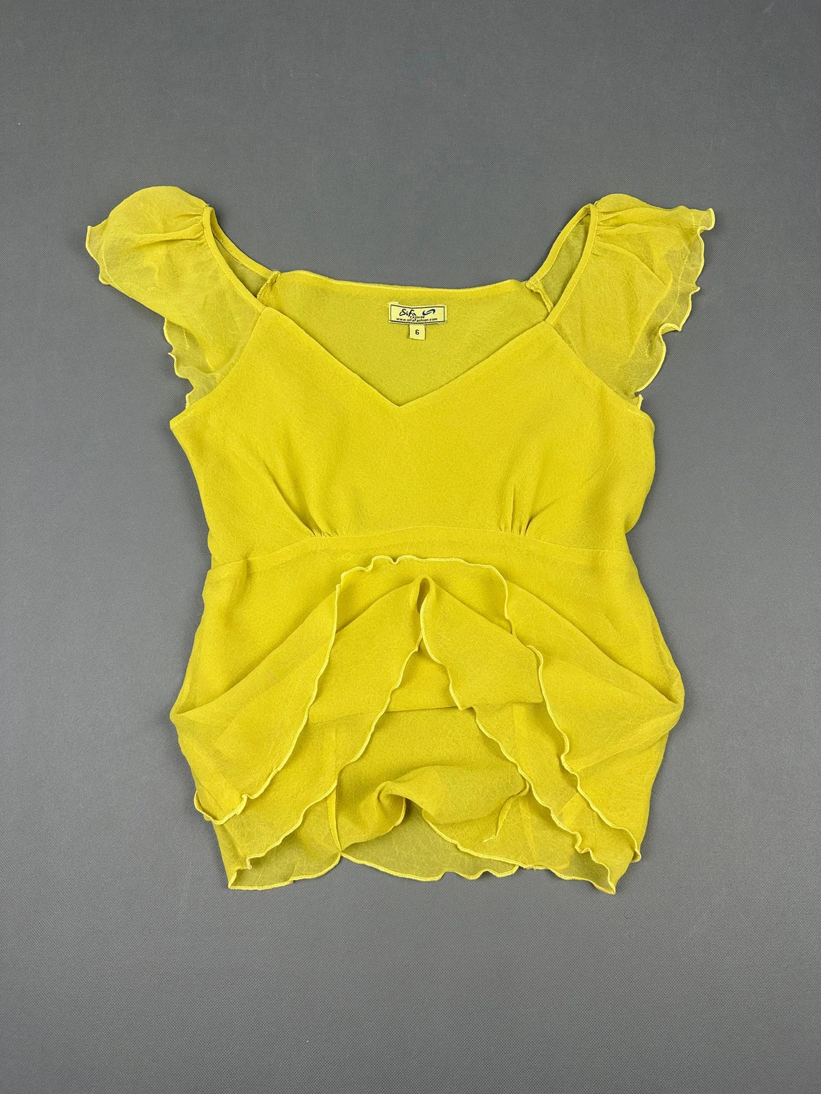 Detail view of a yellow short sleeve top with ruffled sleeves.