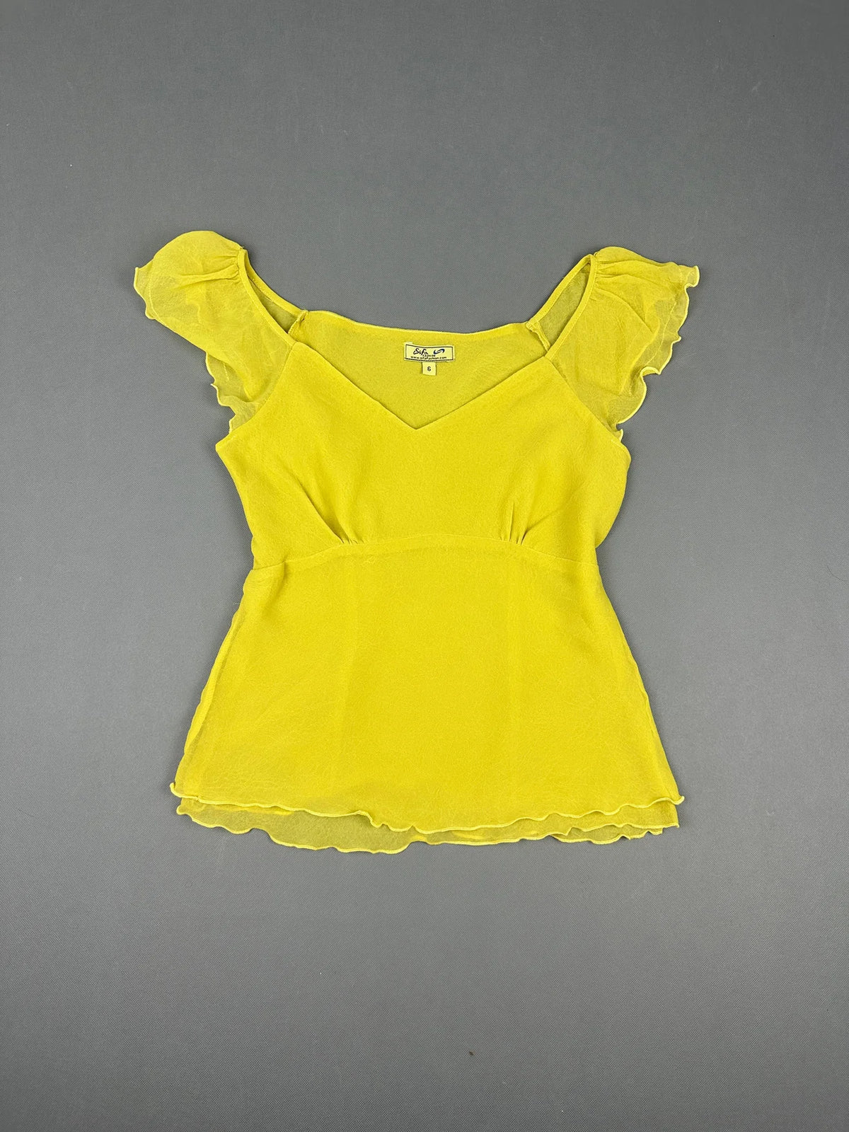 Front view of a short sleeve yellow top with ruffled sleeves.