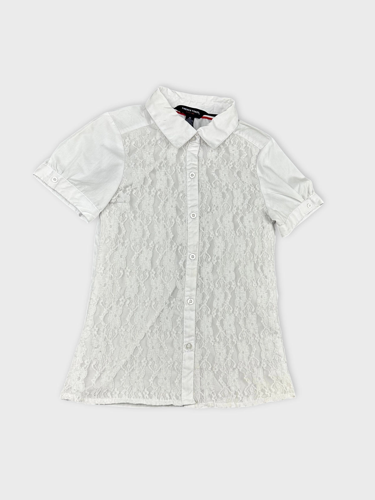 Detail view of a white short sleeve shirt with lace overlay.