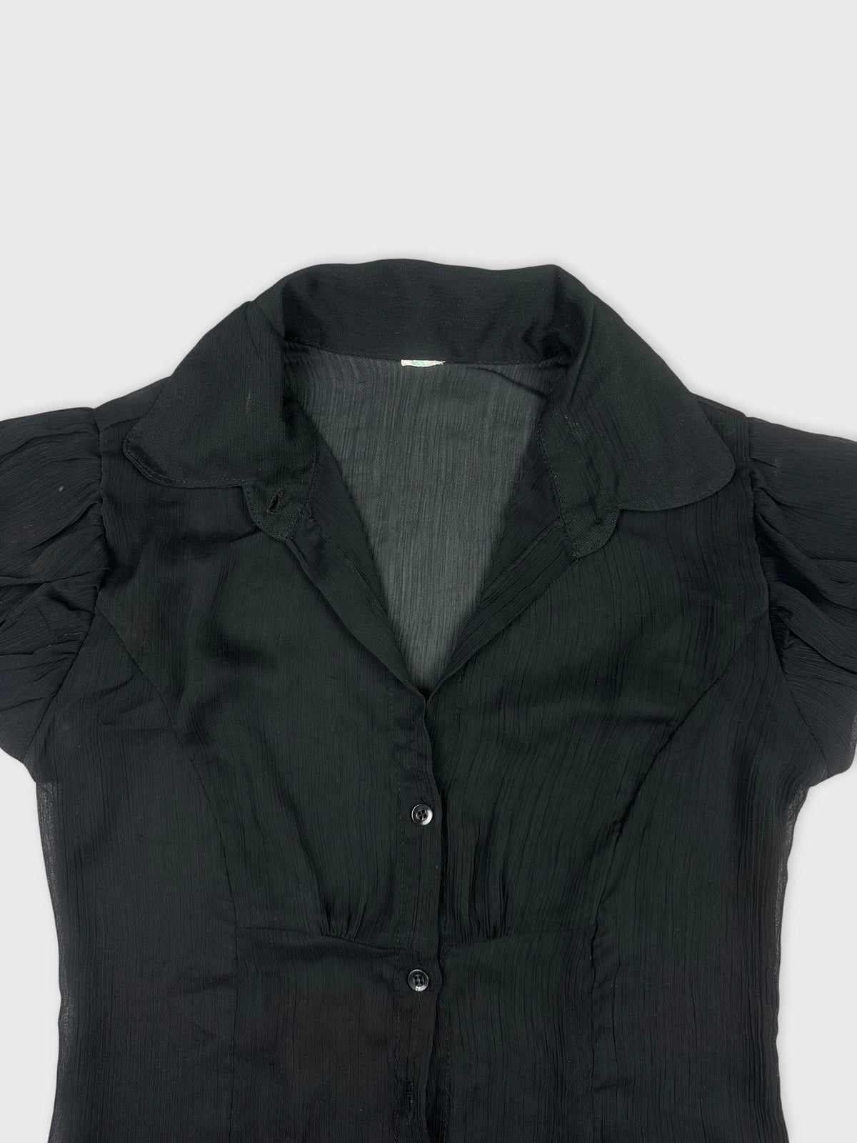 Detail view of a black short sleeve shirt with textured fabric and a collar
