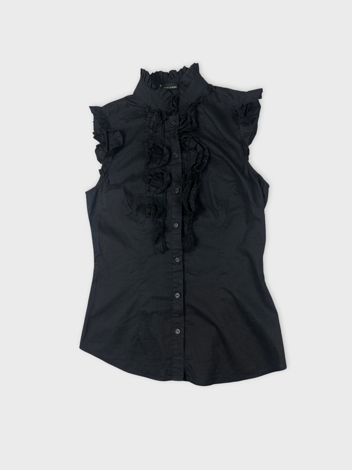 Detail view of a black sleeveless shirt with ruffled trim.