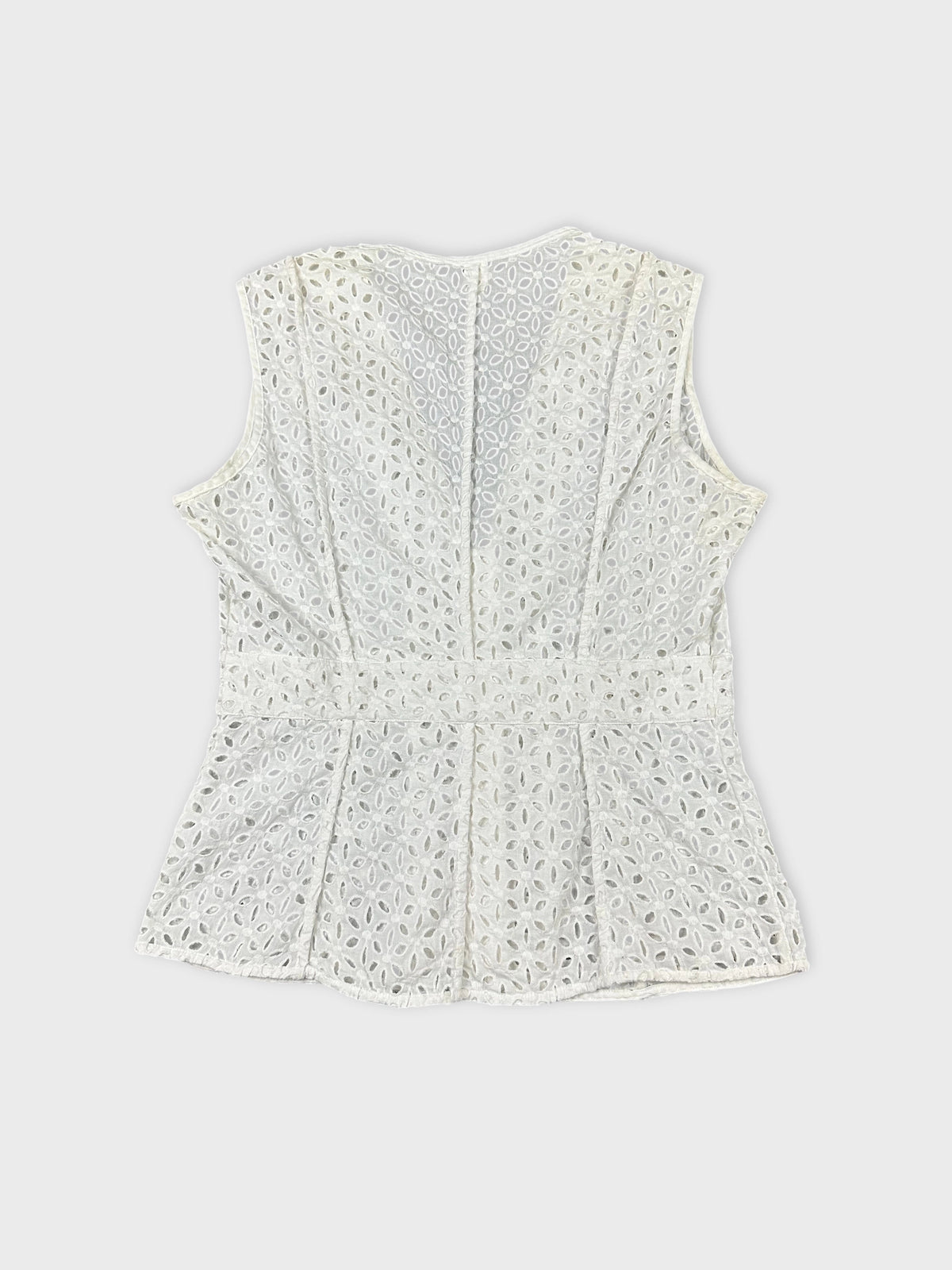 Back view of a women’s sleeveless top in white with eyelet pattern.