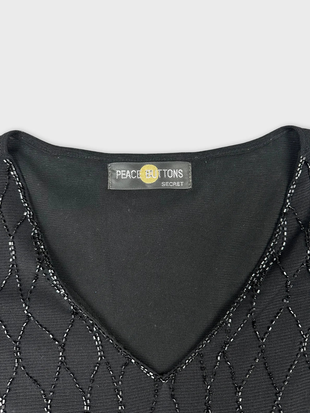 Detail view of a black women's top featuring a patterned neckline.