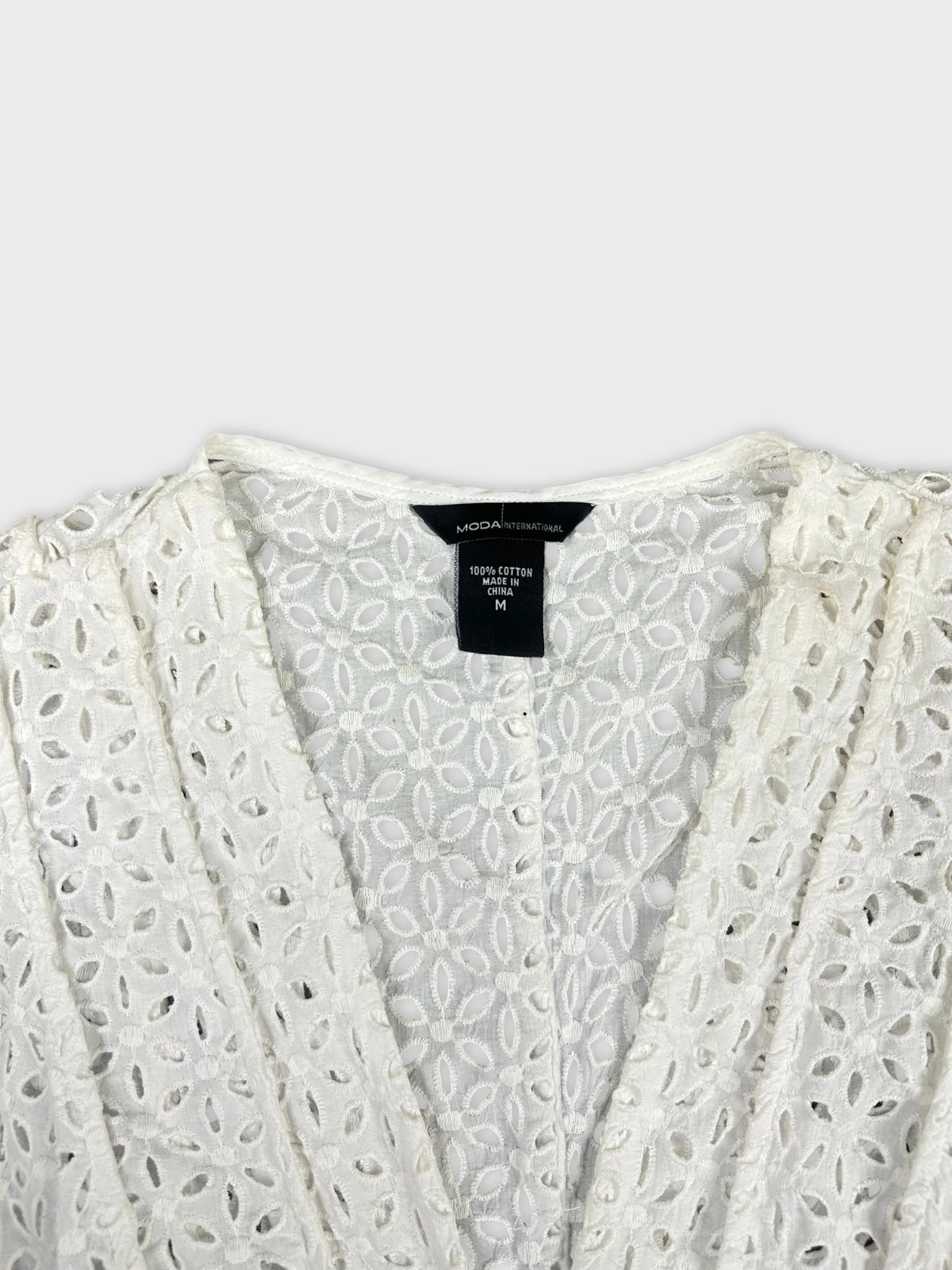 Detail view of a white women’s short sleeve top featuring a floral pattern.