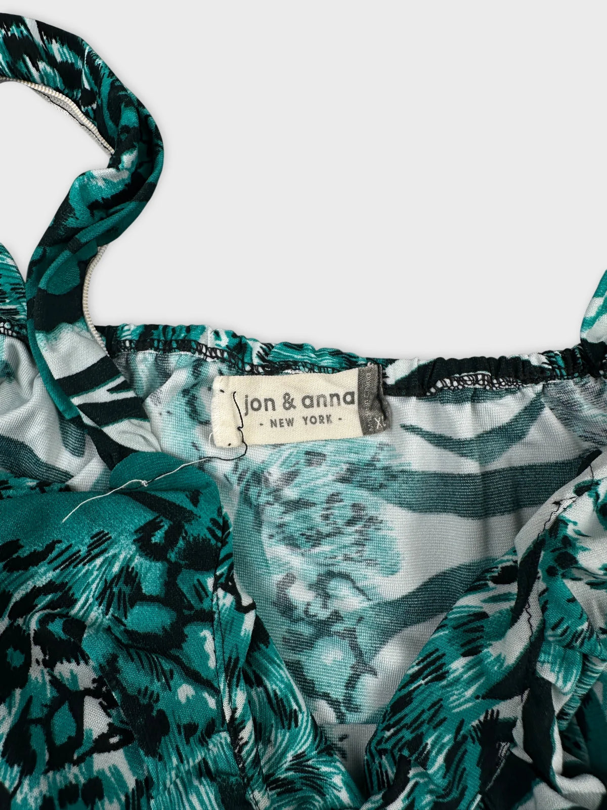 Detail view of women's short sleeve top in teal with floral pattern.