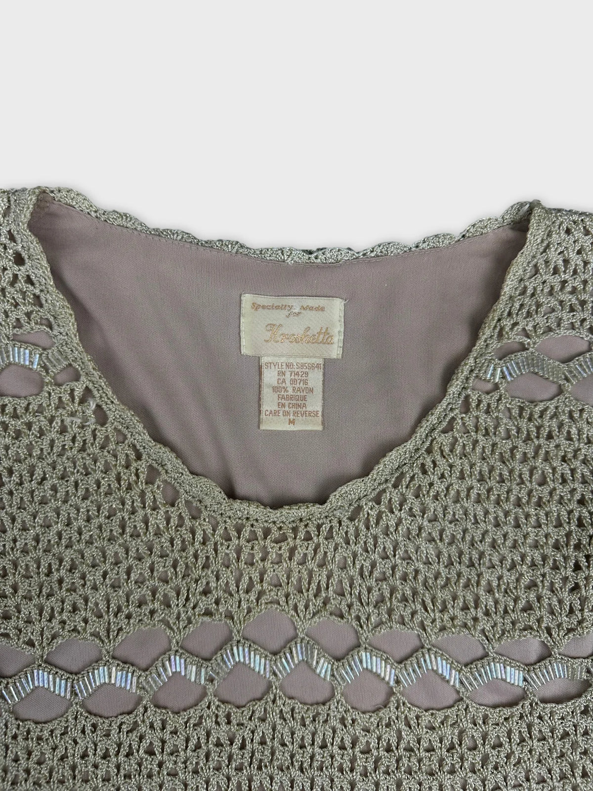 Detail view of a women’s top featuring a silver crochet pattern.