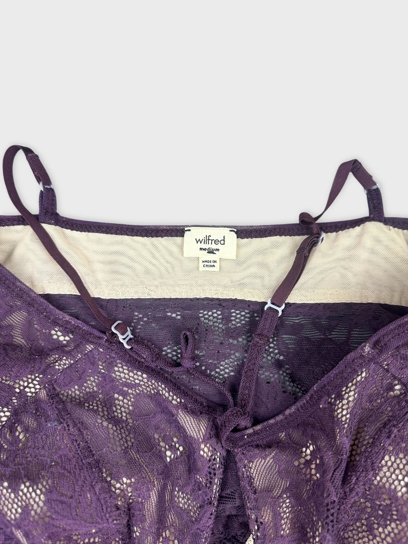 Detail view of purple lace top with adjustable straps and intricate pattern.