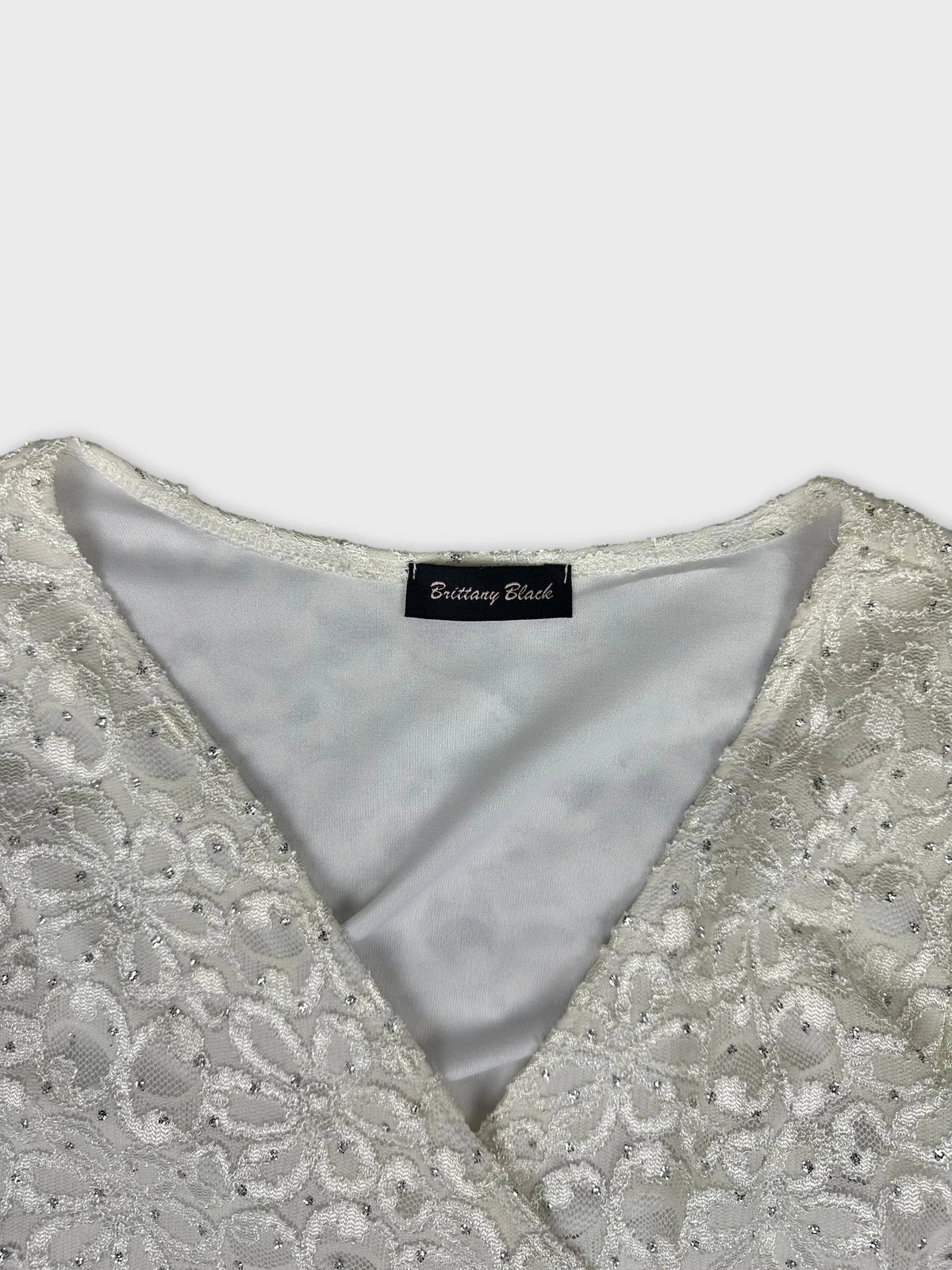 Detail view of a white top featuring floral lace design.