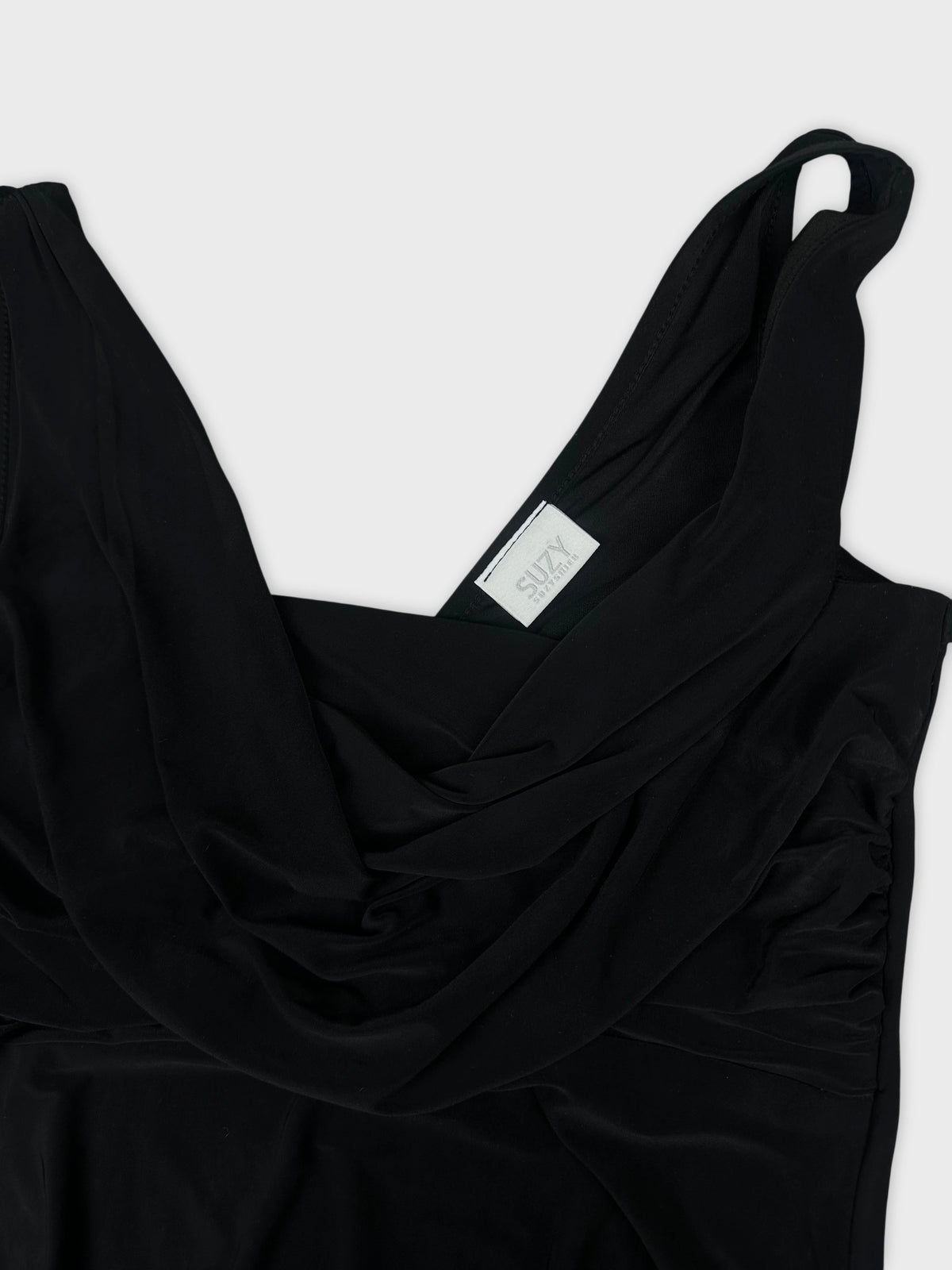 Detail view of a black women's top featuring draped design and scoop neckline.