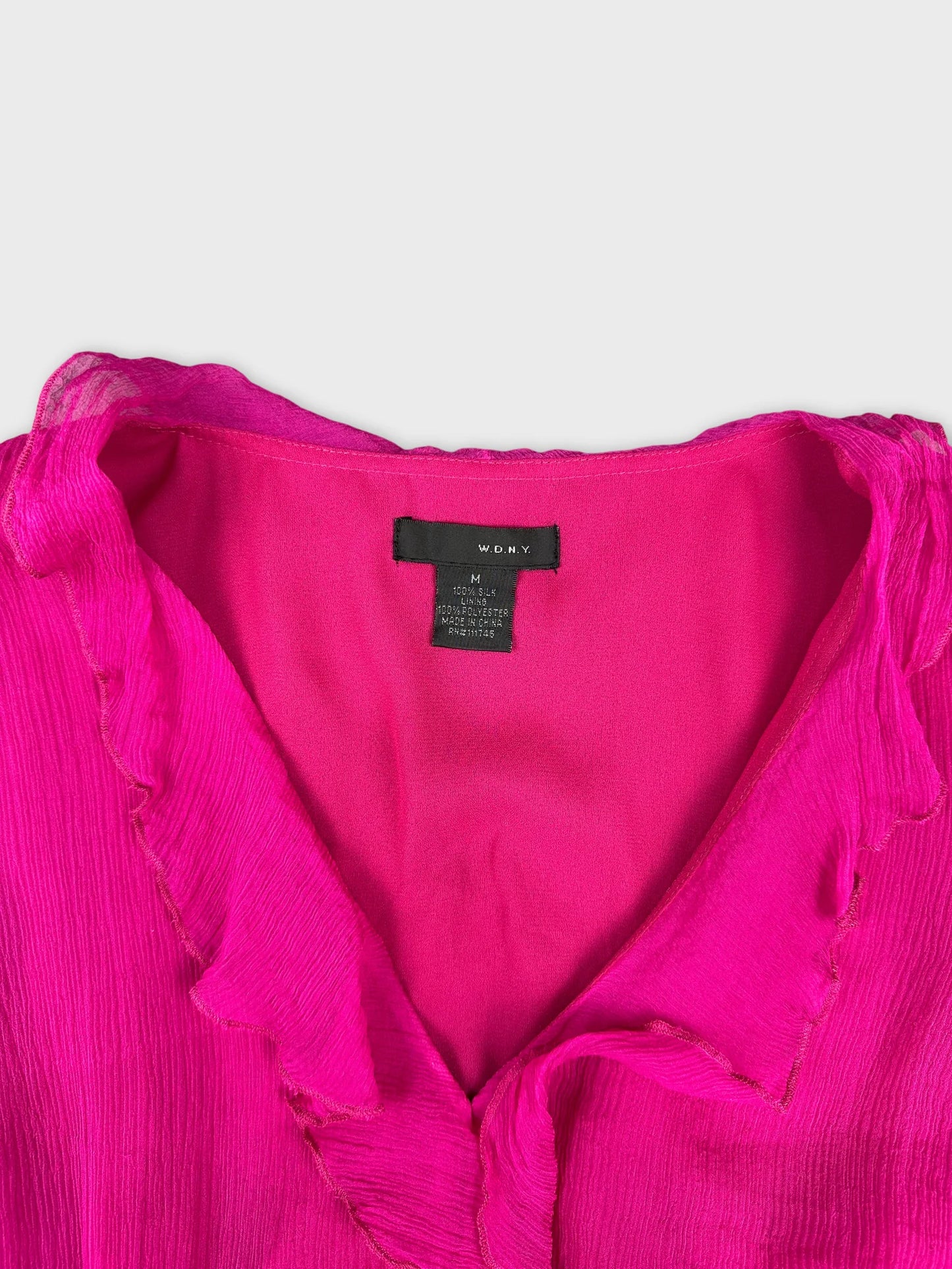 Detail view of a pink top featuring a ruffled neckline
