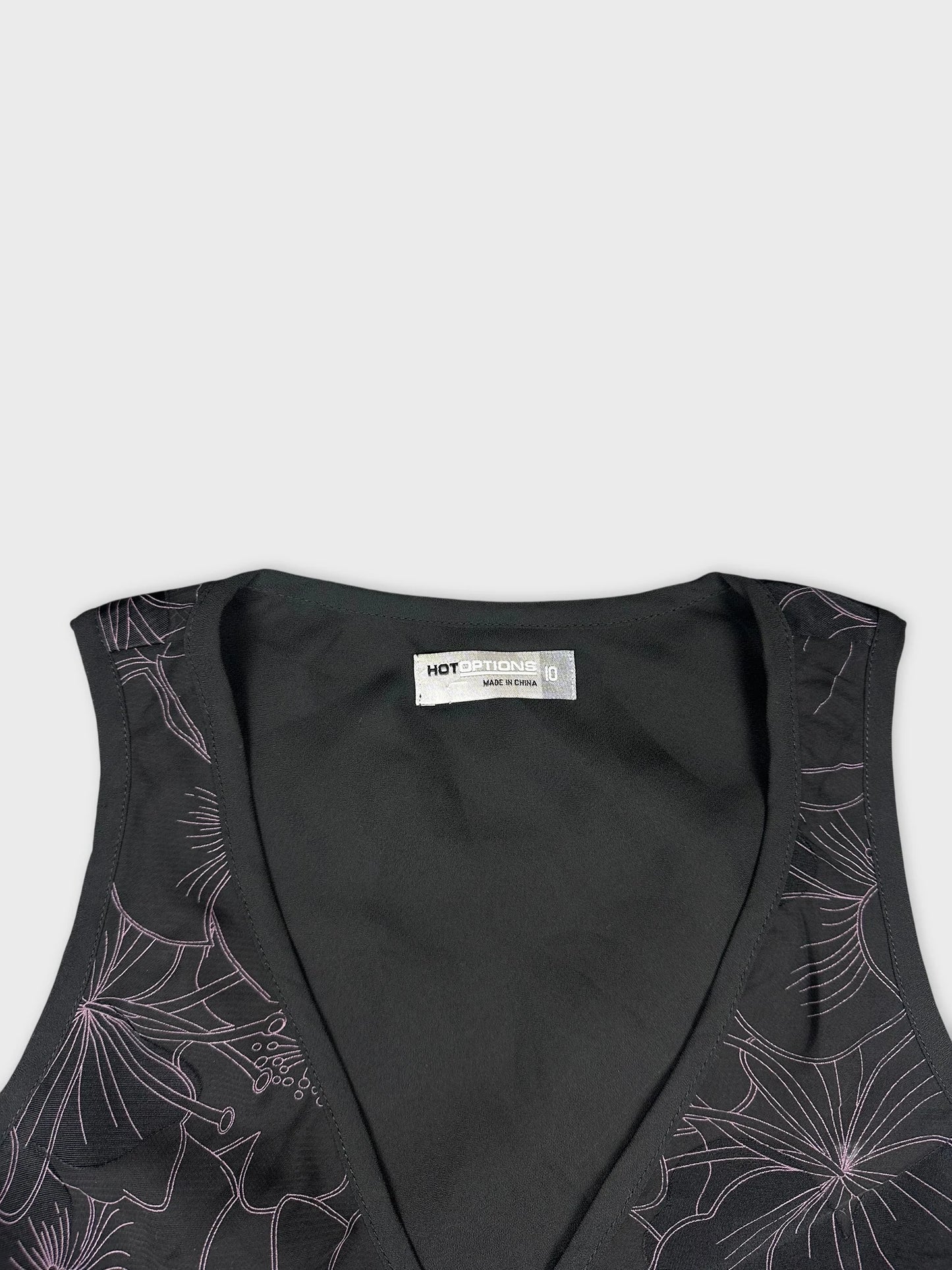 Detail view of a black sleeveless top with floral pattern trim.