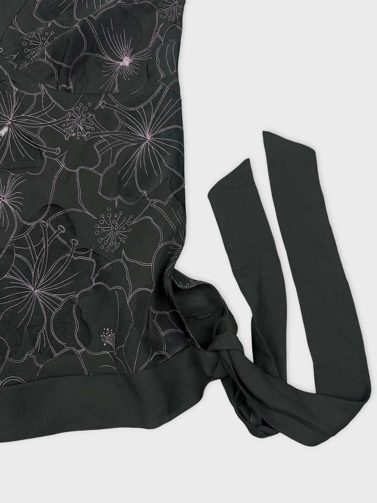 Detail view of black short sleeve top with floral pattern and ties.