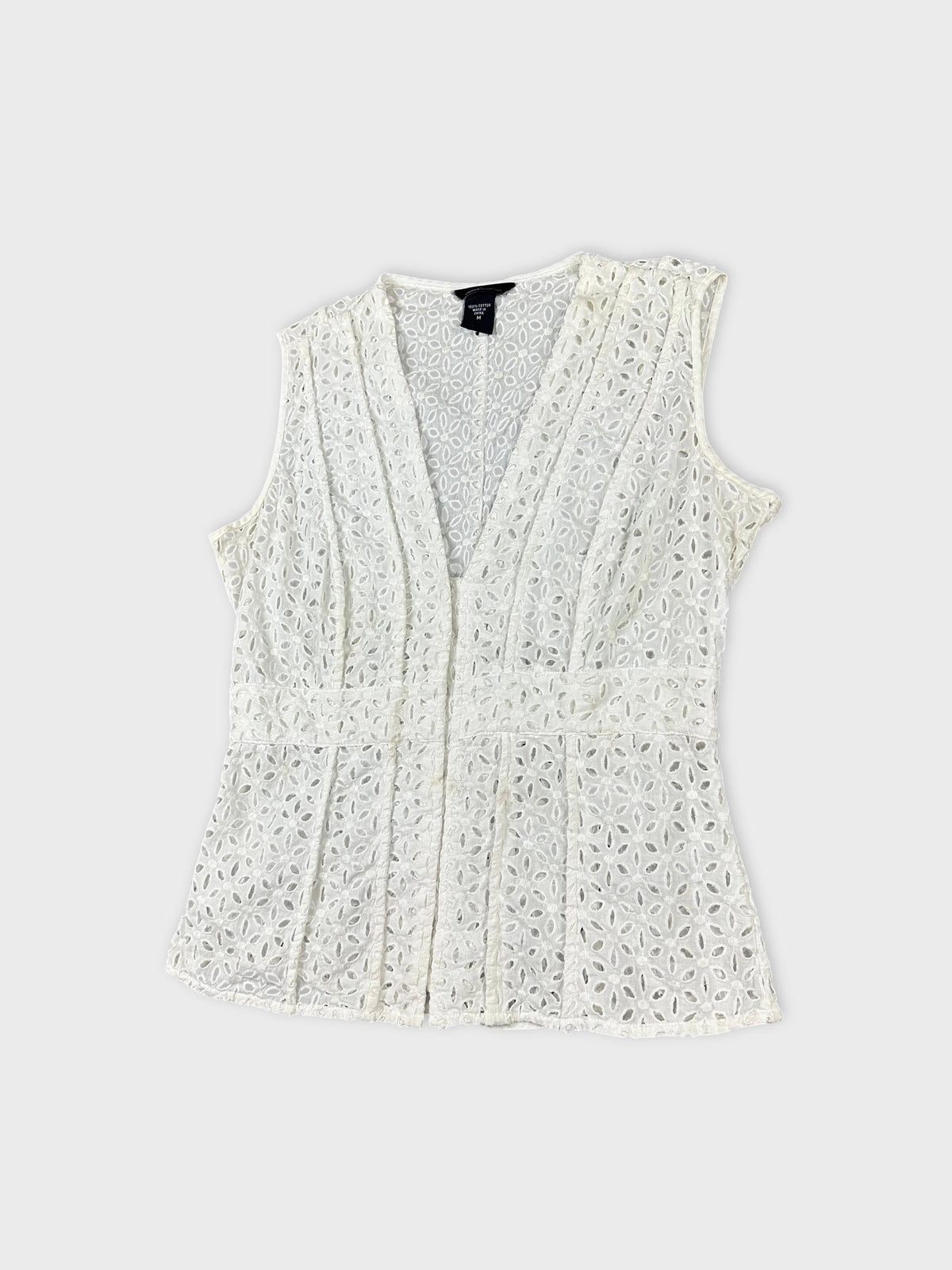 Detail view of a white vintage sleeveless top with floral lace pattern.