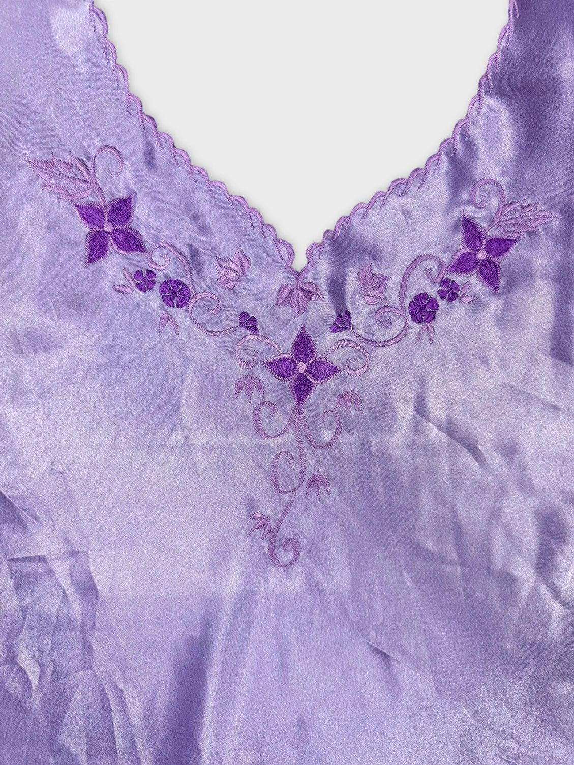 Detail view of a lavender top featuring embroidered floral designs.