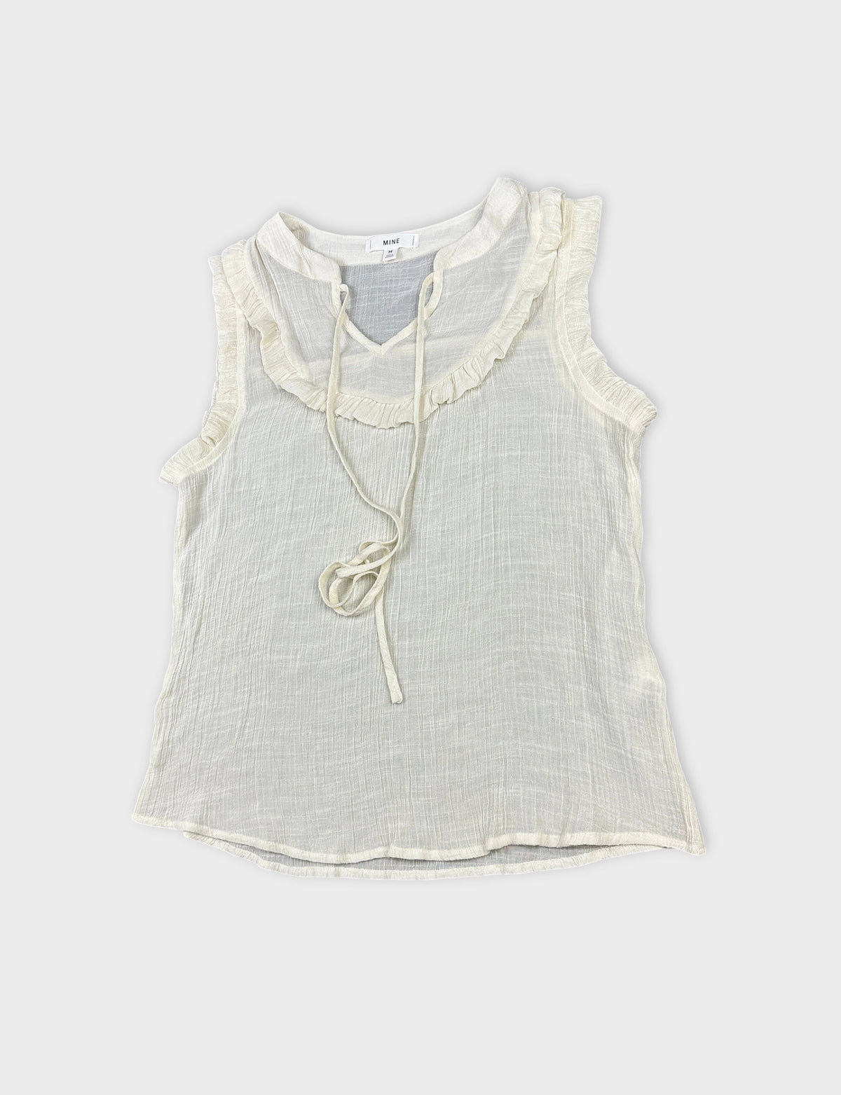 Detail view of a vintage women's short sleeve top in light cream with ruffled trim.