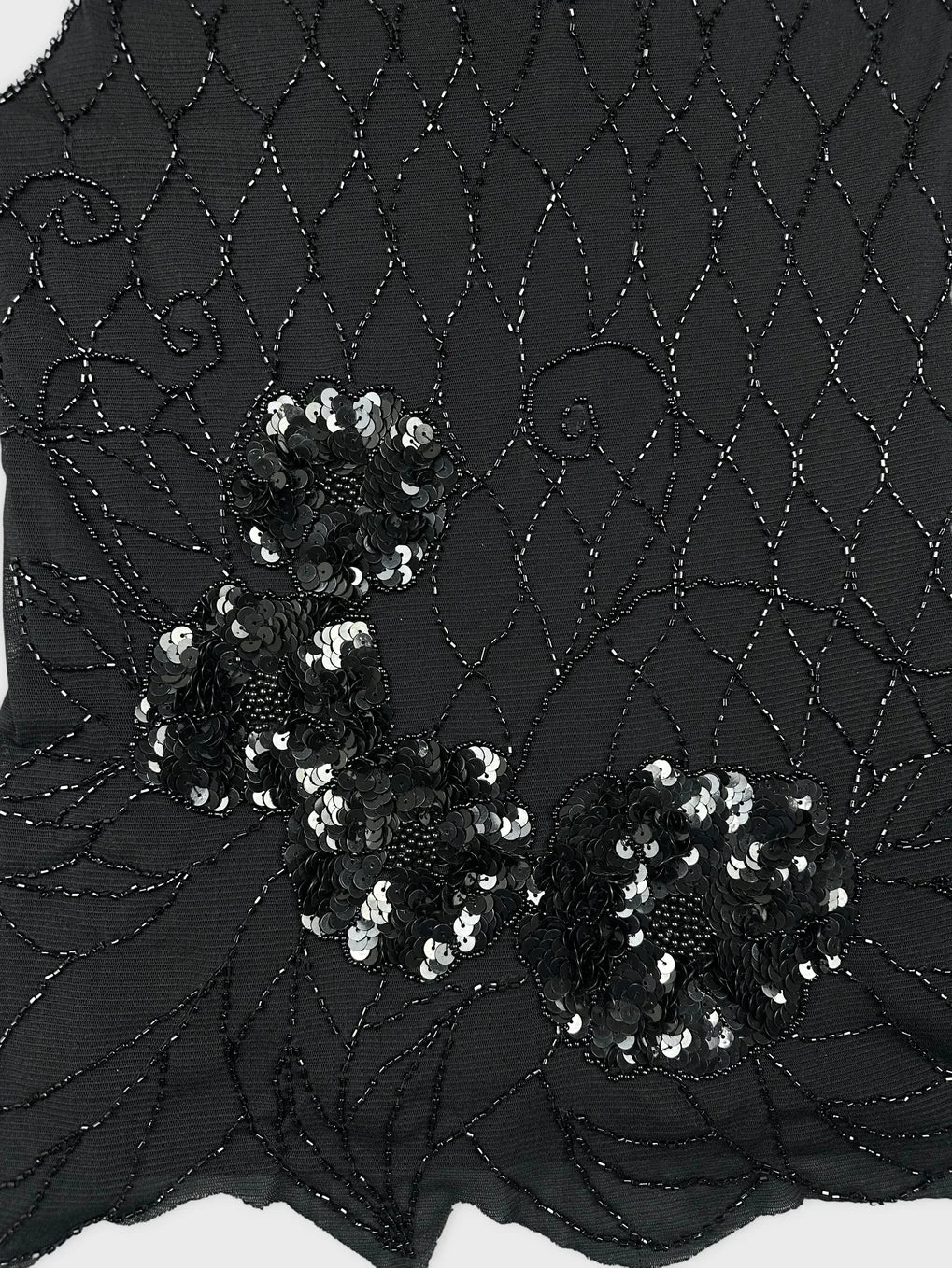 Detail view of a black women's top featuring floral sequined embellishments.