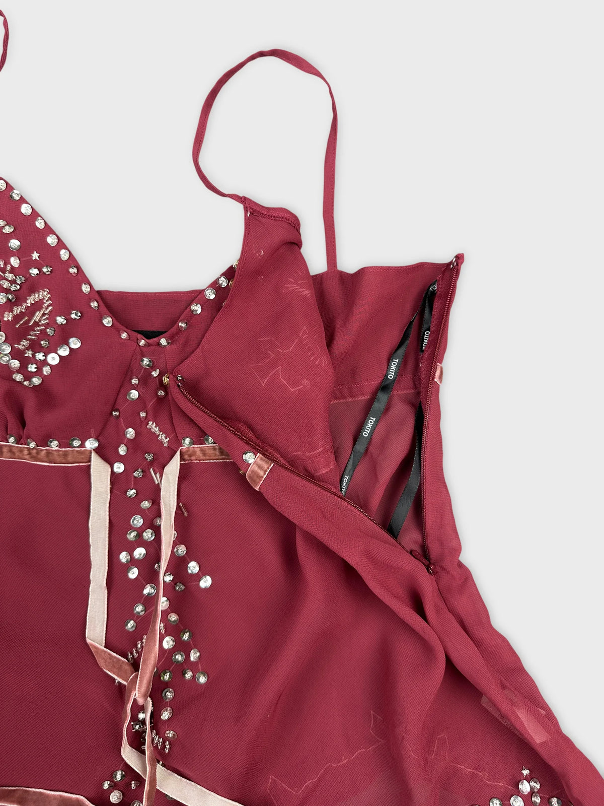 Detail view of burgundy sleeveless top with sparkling embellishments and satin trim