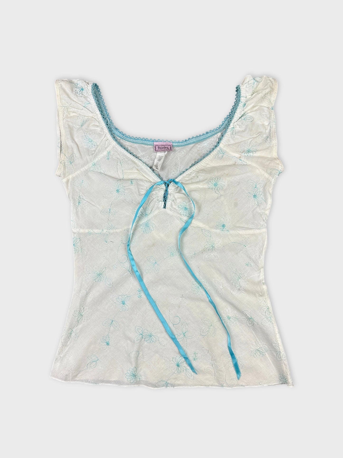 Front view of a short sleeve top in white with blue floral embroidery.