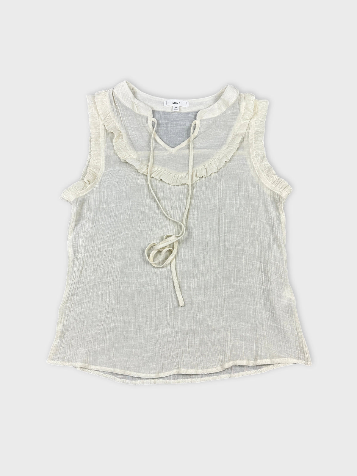 Front view of a vintage cream top with ruffled trim and drawstring.