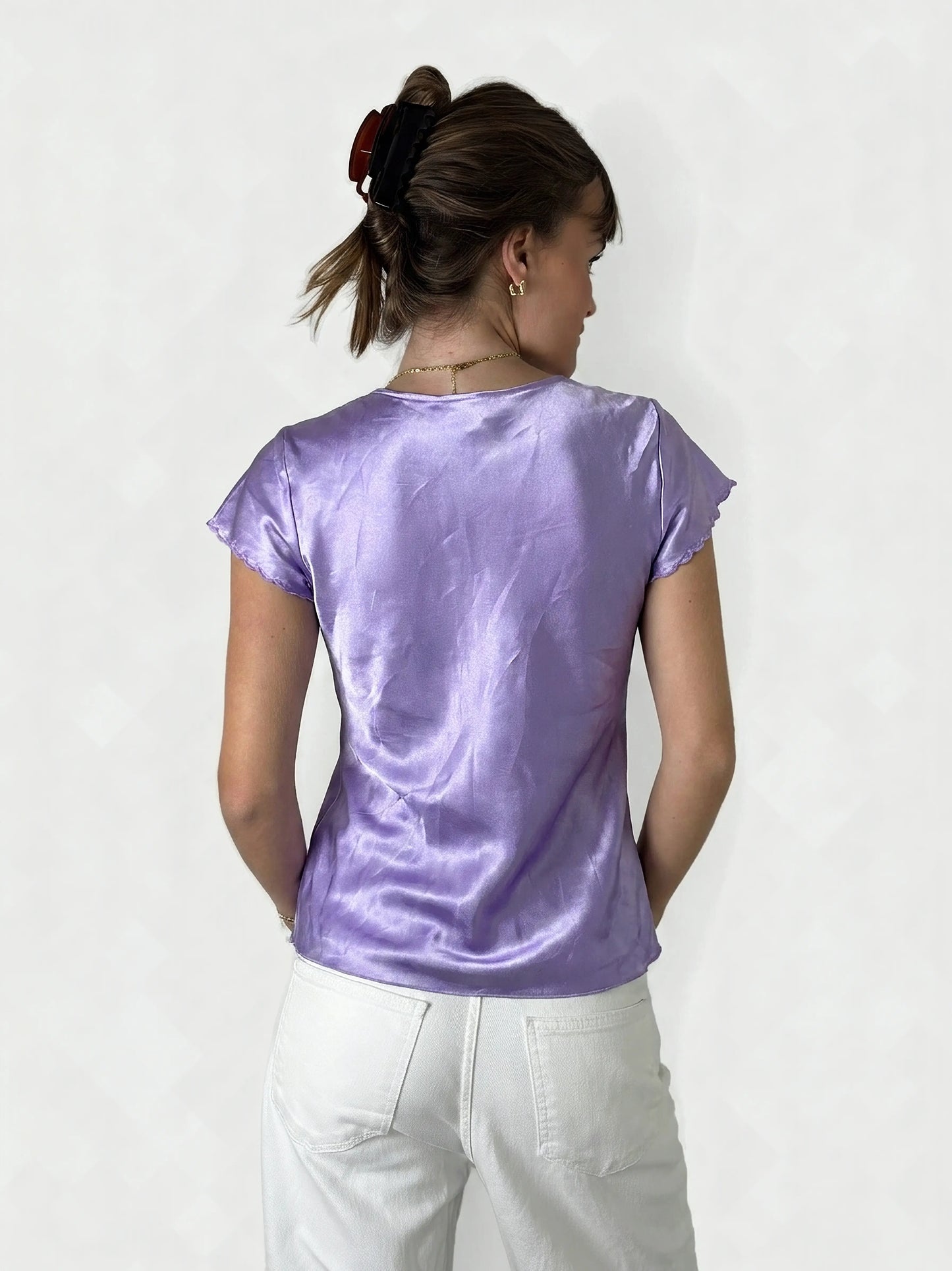 Back view of a purple short sleeve top with ruffled trim.