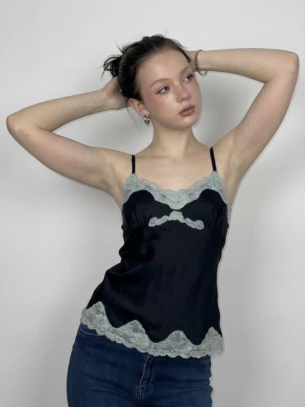 Front view of a black camisole top featuring lace trim.