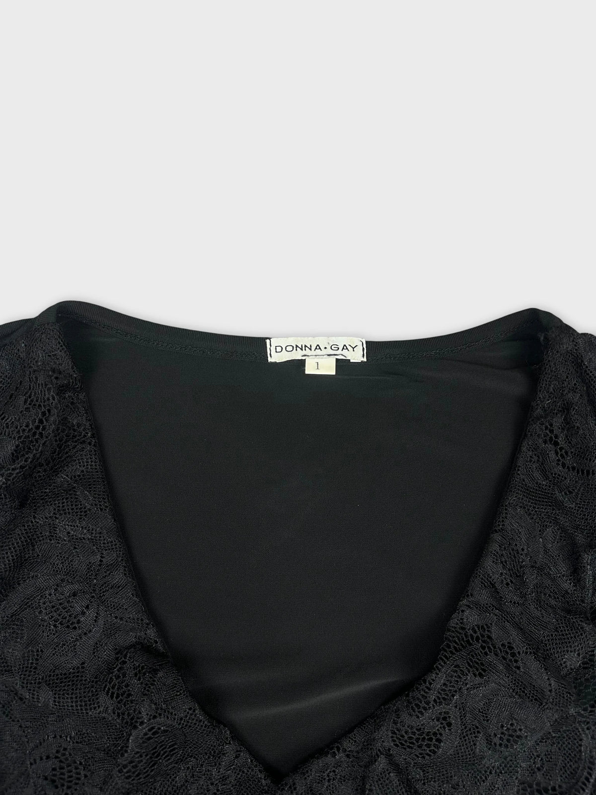 Detail view of a black top with lace trim around the neckline.