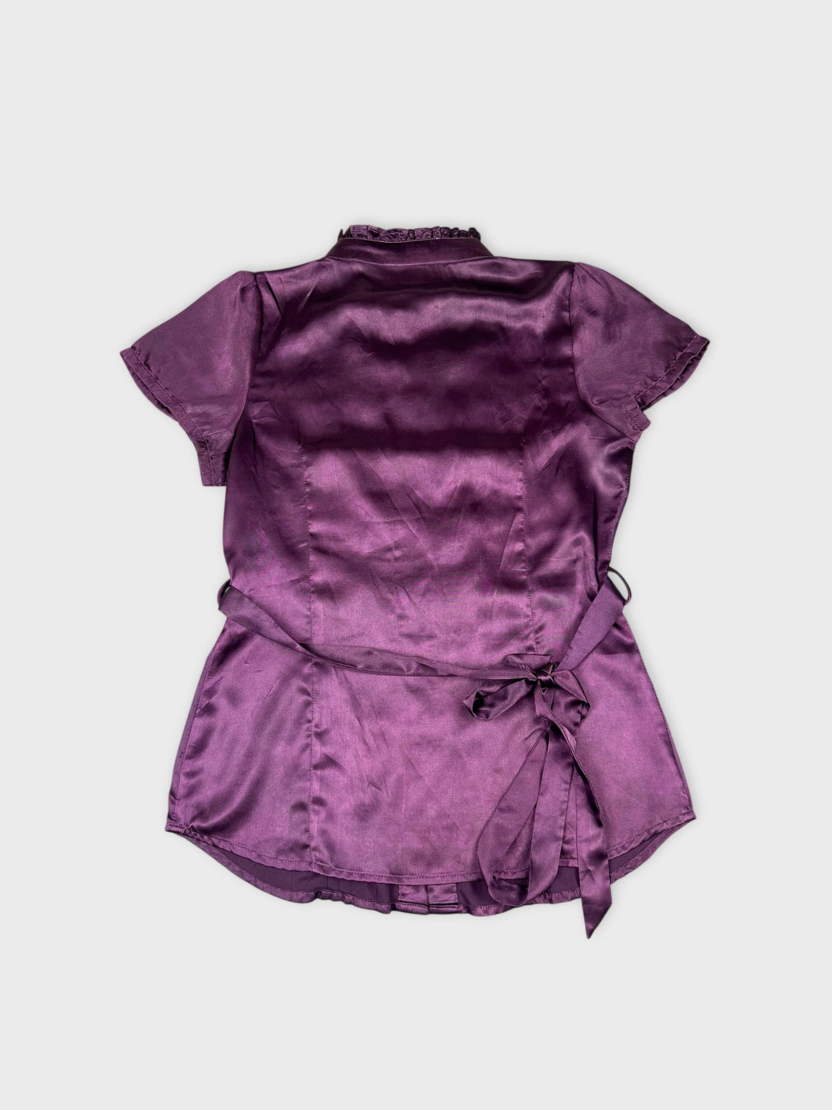 Back view of a purple button-up shirt with a tied waist detail.