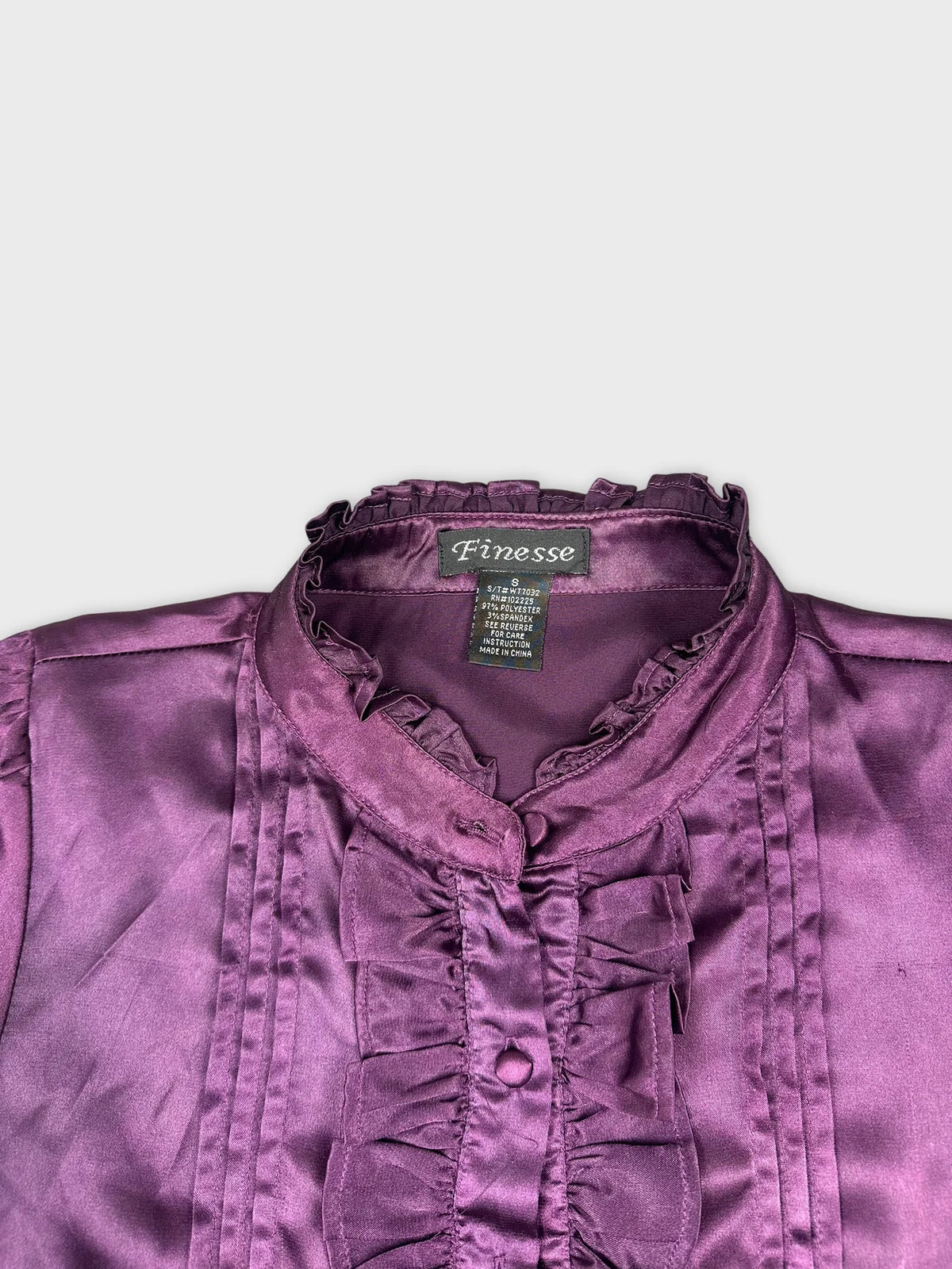 Detail view of a women's button-up shirt in purple with ruffled trim