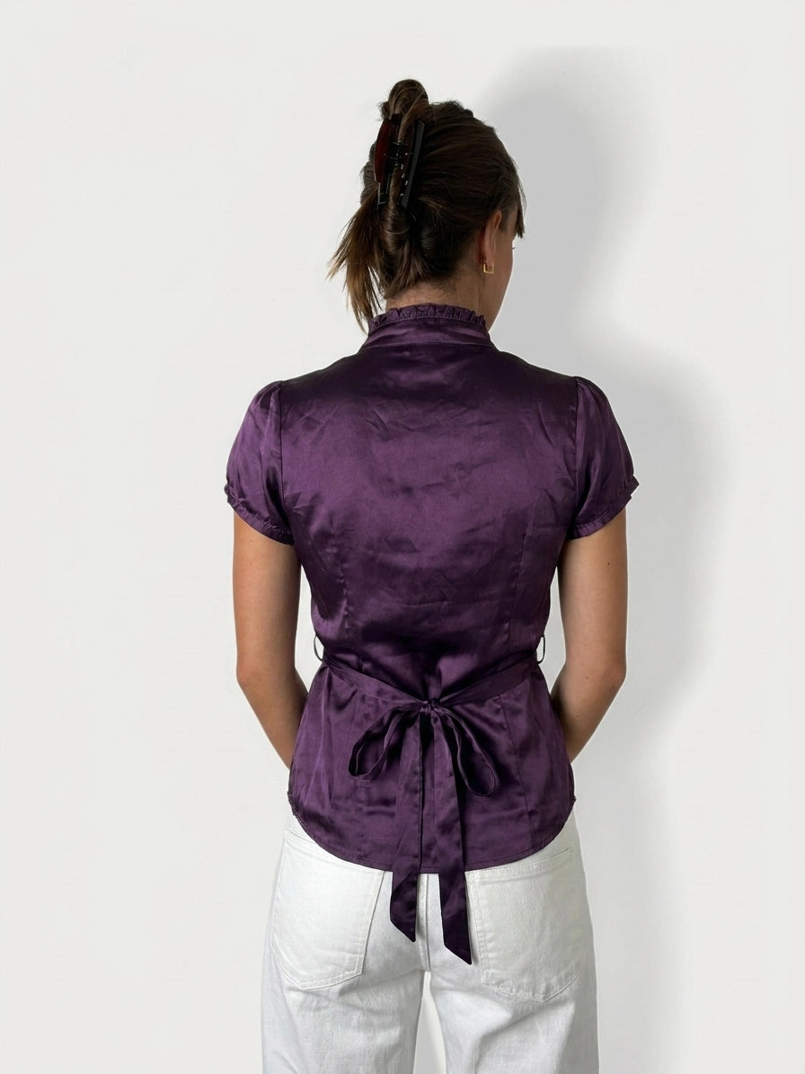 Back view of a purple button-up shirt featuring a waist tie detail.