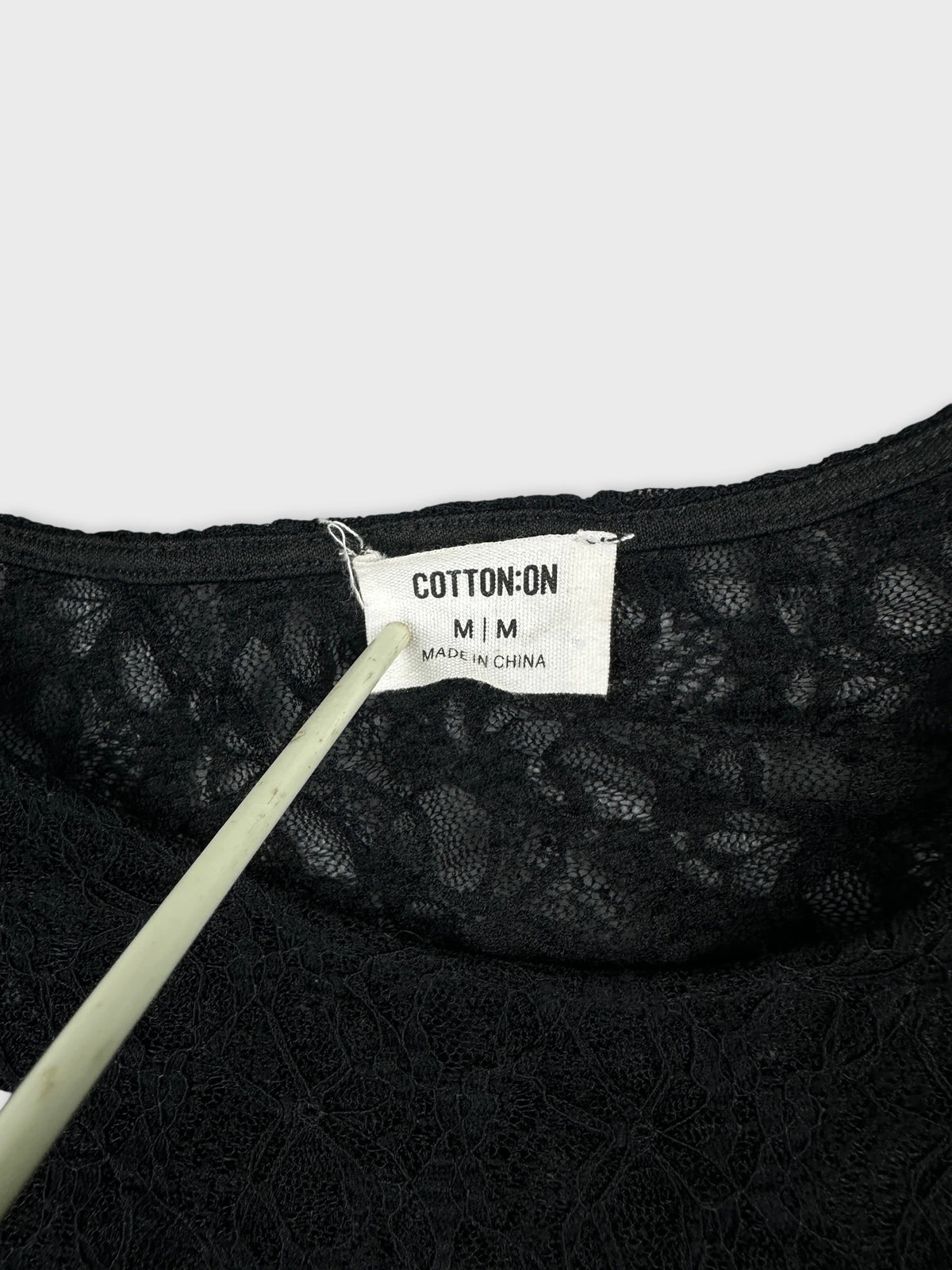 Detail view of a women's long sleeve black top with lace pattern.