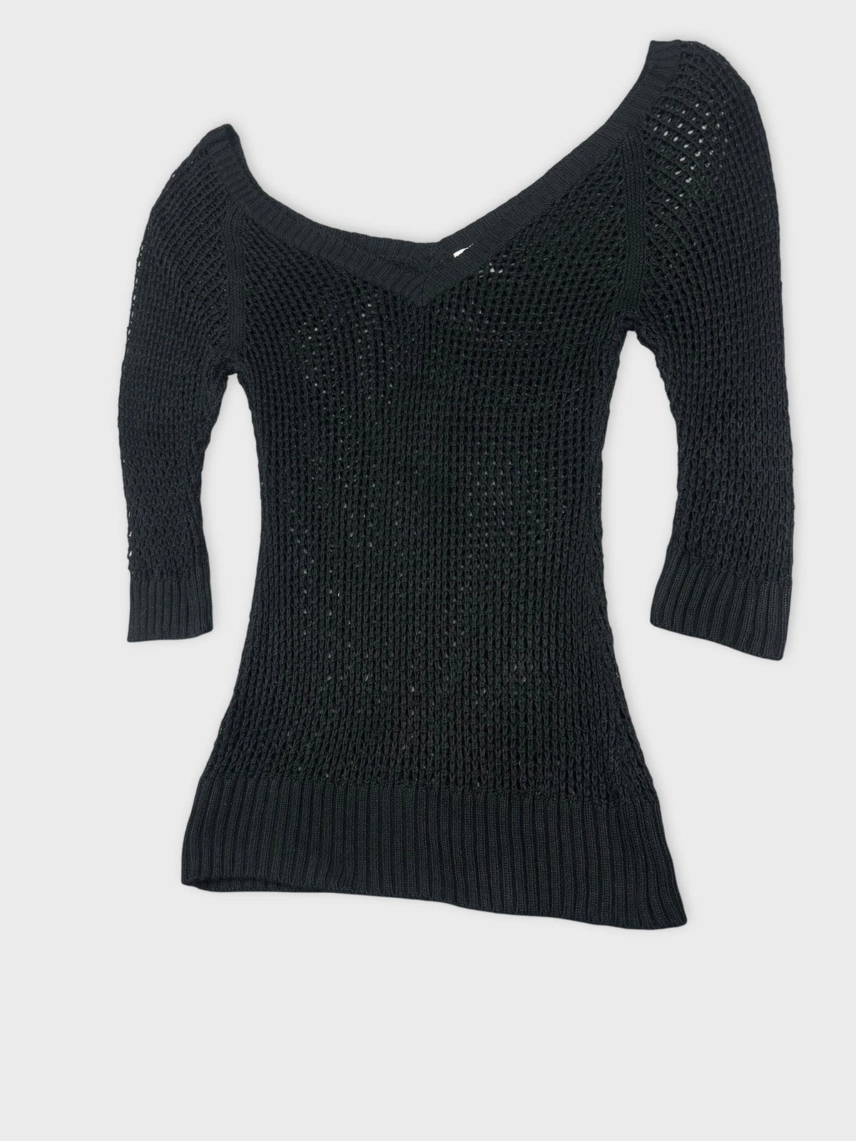 Detail view of a black knit sweater with an off-shoulder design.