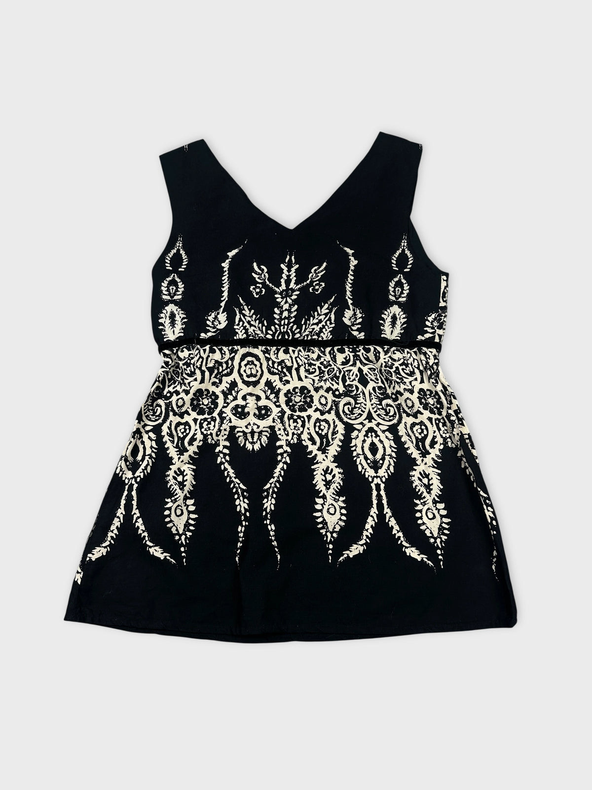Back view of a black sleeveless top with white intricate print.