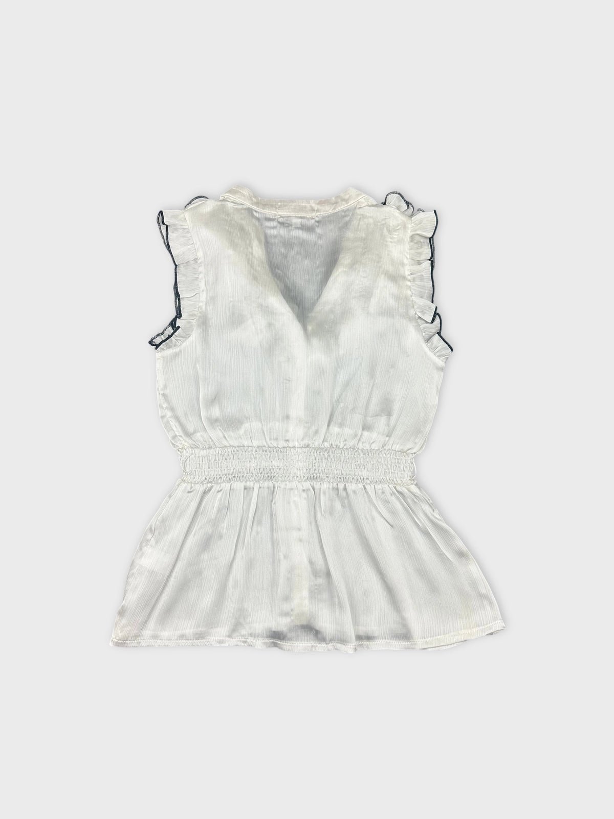 Back view of a white vintage top with frill details and smocked waist.