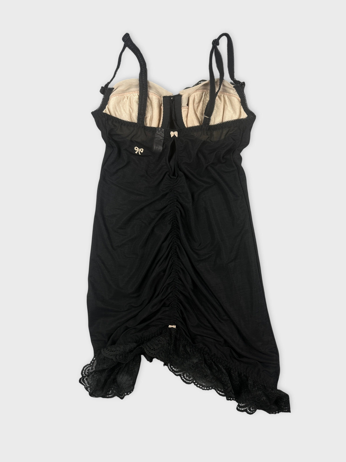 Back view of a black vintage top featuring lace trim and adjustable straps.