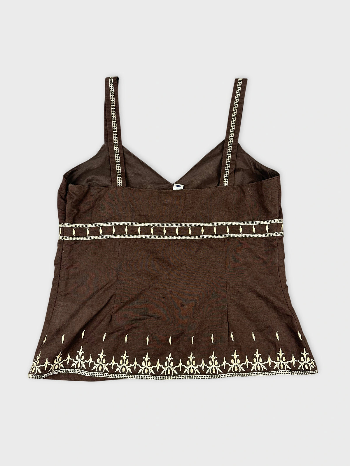 Back view of a brown women's top with decorative white embroidery.
